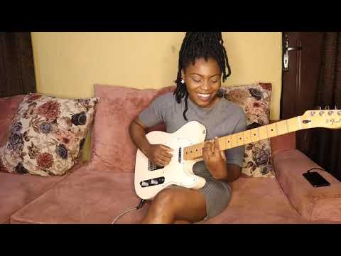 Girl jamming with electric guitar on a couch.