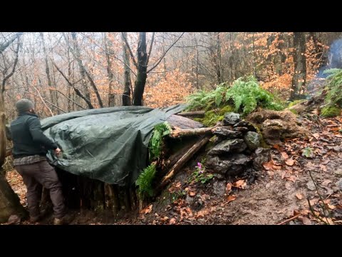 冬季高山露营，大石头下搭建带壁炉的丛林小屋苔藓和木墙野外生存