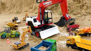 Construction vehicles work together to rescue excavator stuck in sand
