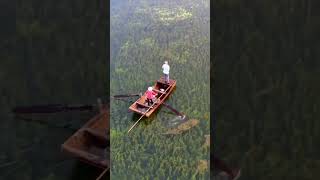老人在山东济宁的微山湖上泛舟，湖水清澈见底，水草摇曳，宛如御剑飞行