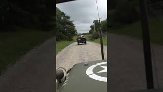 A small WWII Jeep convoy heads down a country road