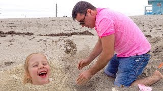 Stacy e papai brincam no mar na areia