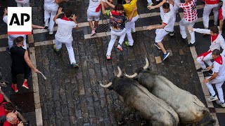 People run with charging bulls at Pamplona festival in Spain